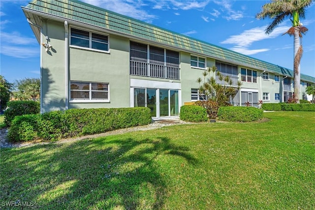 back of property with a lawn and stucco siding