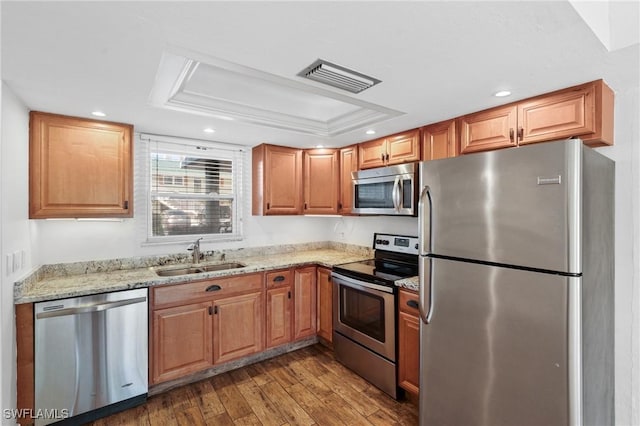 kitchen with visible vents, appliances with stainless steel finishes, dark wood-style flooring, a tray ceiling, and a sink