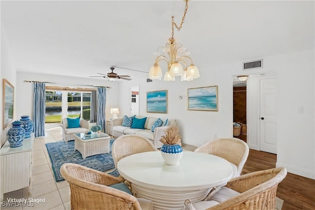 tiled dining room featuring ceiling fan with notable chandelier