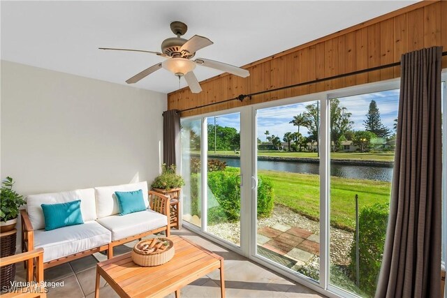 sunroom / solarium featuring ceiling fan and a water view