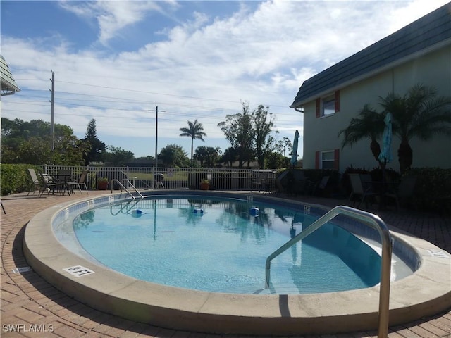 community pool with a patio area and fence