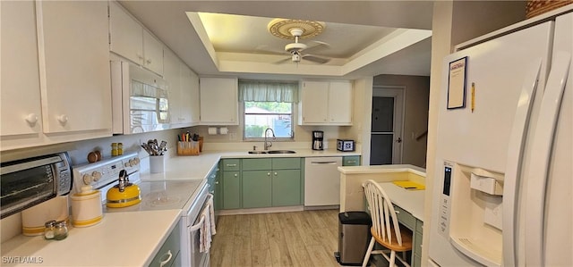 kitchen featuring white appliances, white cabinets, a raised ceiling, sink, and light hardwood / wood-style flooring