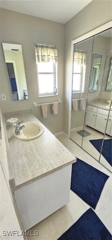 bathroom with tile patterned flooring, vanity, and a healthy amount of sunlight