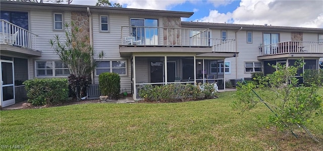 rear view of house with a sunroom, a balcony, and a yard