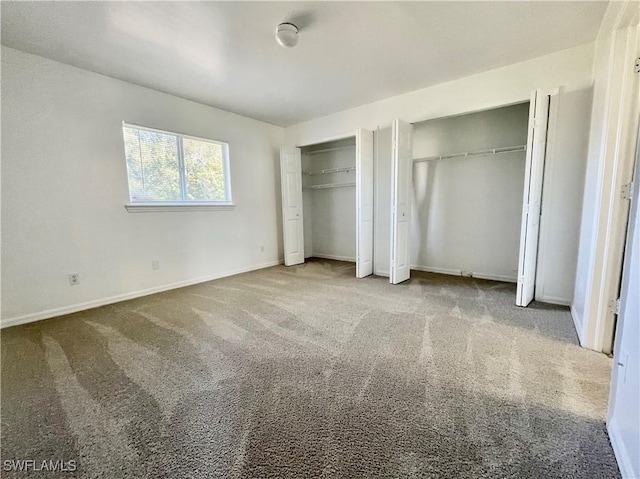 unfurnished bedroom with carpet flooring and two closets