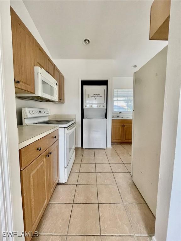 kitchen featuring light tile patterned flooring, white appliances, and sink