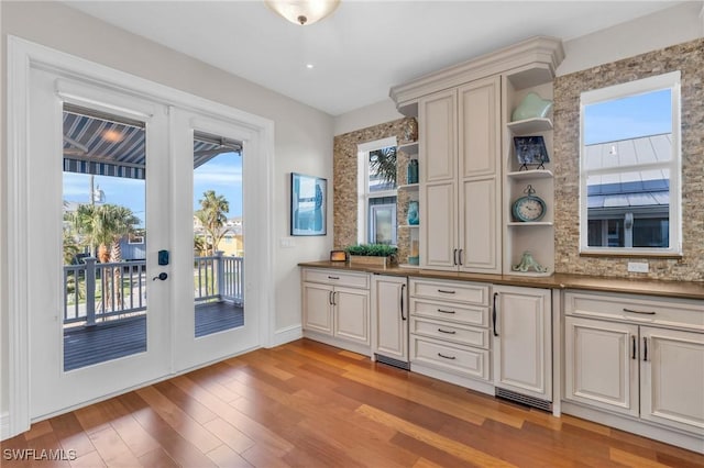 interior space with a healthy amount of sunlight, light hardwood / wood-style floors, backsplash, and french doors