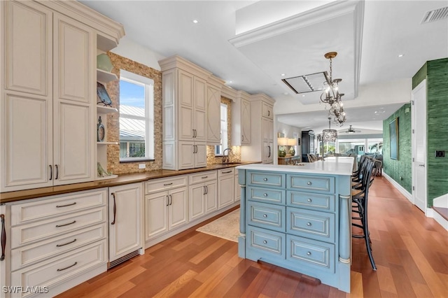 kitchen with a kitchen breakfast bar, light hardwood / wood-style flooring, decorative light fixtures, and sink