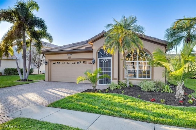 mediterranean / spanish house with a garage and a front lawn