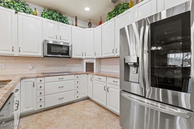 kitchen featuring light tile patterned flooring, light stone counters, appliances with stainless steel finishes, decorative backsplash, and white cabinets