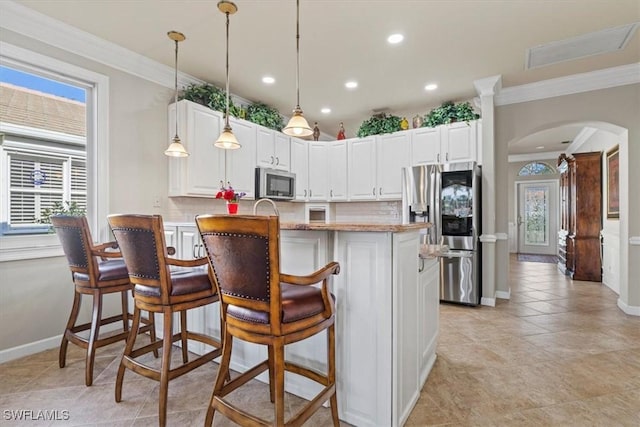 kitchen featuring white cabinetry, hanging light fixtures, decorative backsplash, and stainless steel appliances