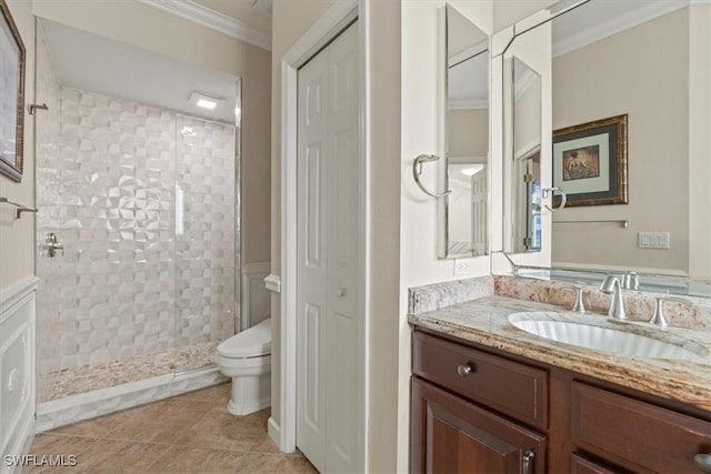 bathroom featuring tile patterned flooring, tiled shower, vanity, ornamental molding, and toilet