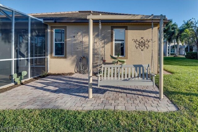 rear view of house with a lanai, a lawn, and a patio