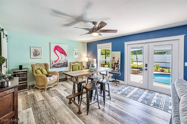 dining space featuring french doors, wine cooler, ceiling fan, a barn door, and light wood-type flooring