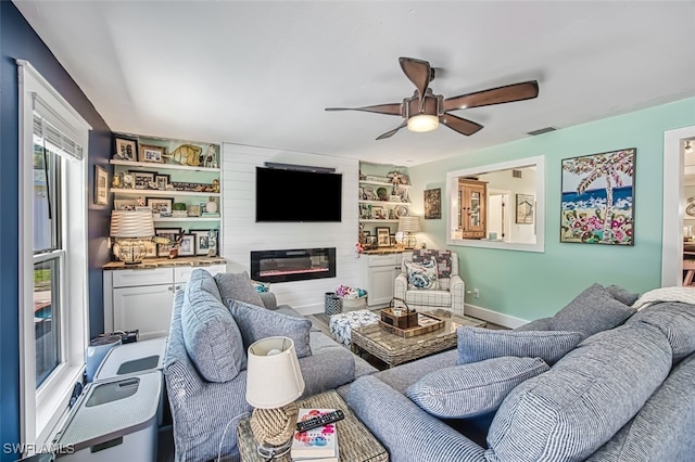 living room featuring a large fireplace and ceiling fan