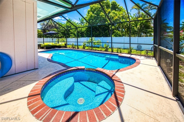 view of pool with glass enclosure, an in ground hot tub, and a patio area