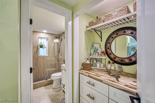 bathroom with a tile shower, vanity, and toilet