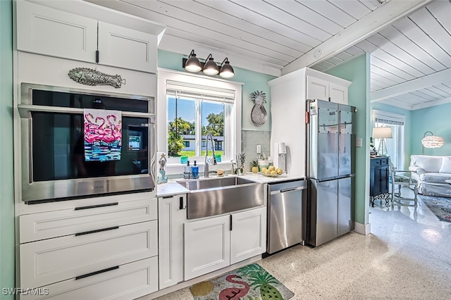 kitchen featuring white cabinets, beam ceiling, stainless steel appliances, and wood ceiling