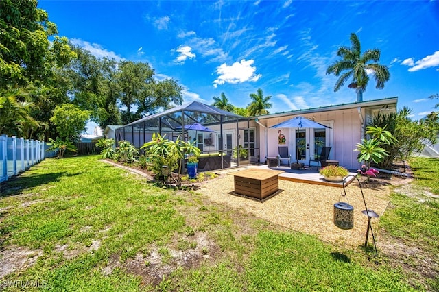 rear view of property with french doors, a yard, and a lanai