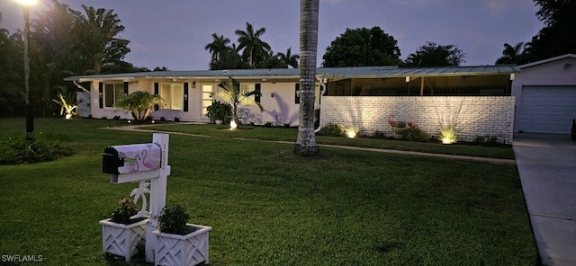 ranch-style home featuring a garage and a yard