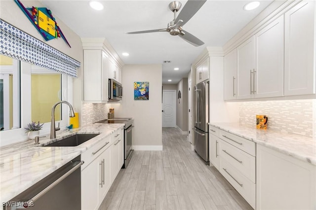 kitchen with sink, ceiling fan, light stone counters, white cabinetry, and stainless steel appliances