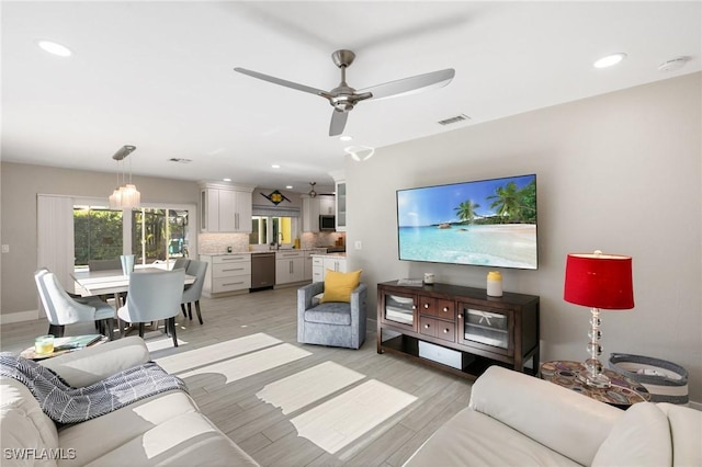 living room featuring ceiling fan, light hardwood / wood-style floors, and sink