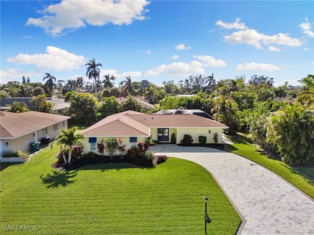 mediterranean / spanish house featuring cooling unit, a front lawn, and decorative driveway