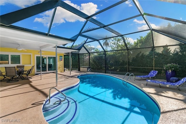 view of pool featuring a patio, glass enclosure, and ceiling fan