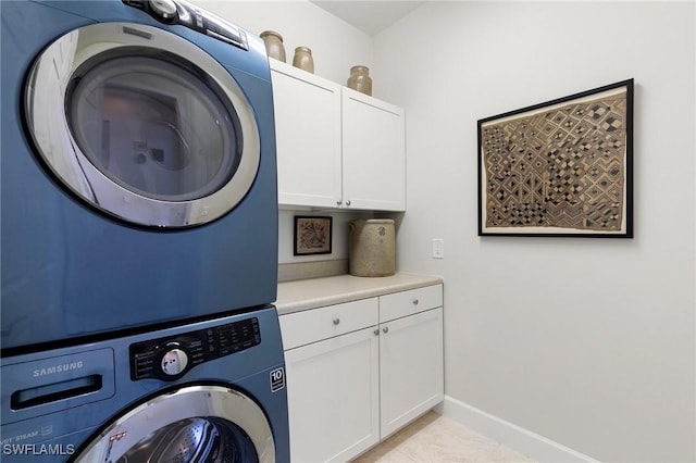 laundry area with cabinets and stacked washer / dryer