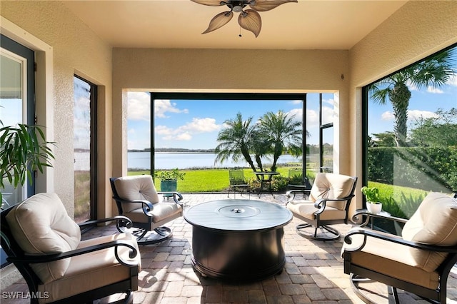 sunroom featuring ceiling fan and a water view