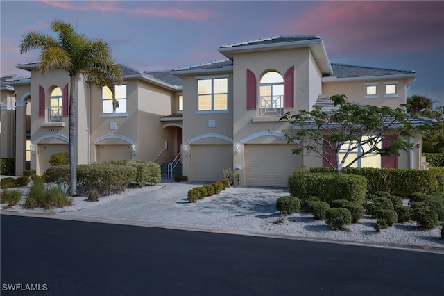 view of front of house featuring a garage, decorative driveway, and stucco siding