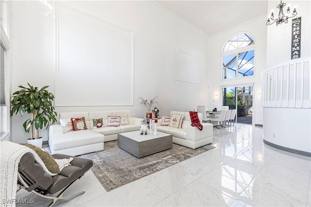 living room featuring crown molding, a high ceiling, and an inviting chandelier