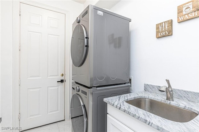 washroom featuring cabinets, light tile patterned floors, sink, and stacked washer and clothes dryer