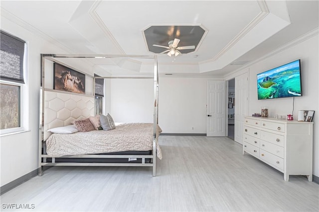 bedroom featuring light wood-type flooring, a tray ceiling, ceiling fan, and ornamental molding