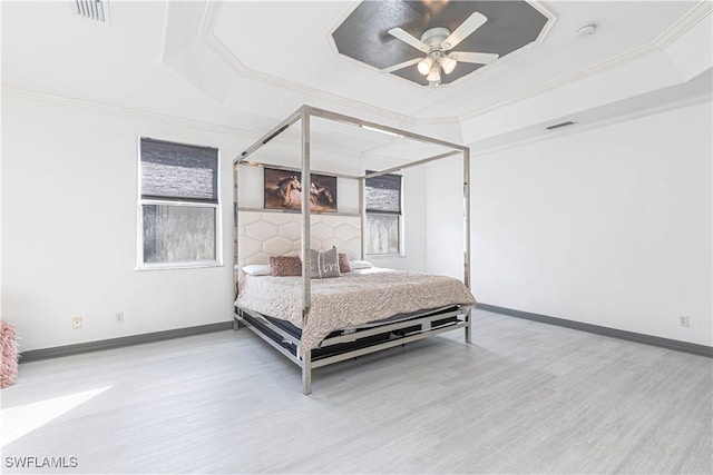 bedroom featuring a raised ceiling, ceiling fan, crown molding, and wood-type flooring