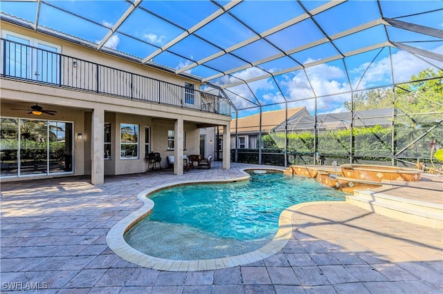 view of pool with an in ground hot tub, a patio, glass enclosure, and ceiling fan