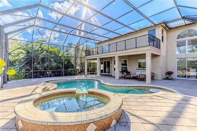 view of pool featuring glass enclosure, an in ground hot tub, and a patio