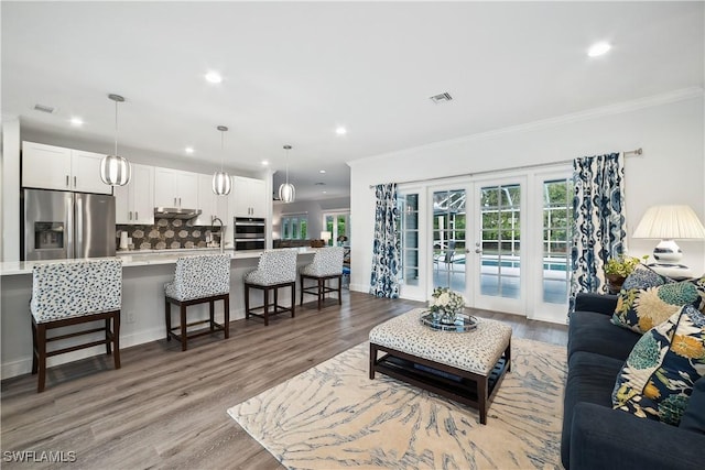 living room featuring light wood-type flooring, ornamental molding, and french doors