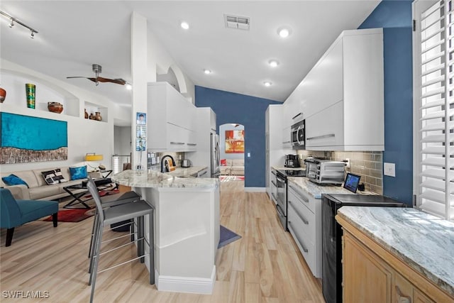 kitchen featuring ceiling fan, stainless steel appliances, light stone counters, white cabinets, and light wood-type flooring