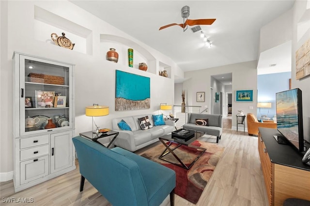 living room featuring built in shelves, ceiling fan, and light hardwood / wood-style flooring