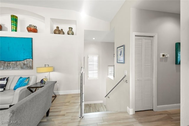 interior space with hardwood / wood-style flooring, built in shelves, and vaulted ceiling