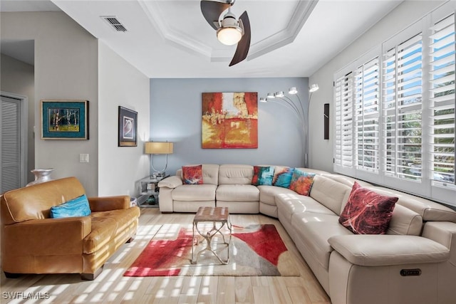 living room with a tray ceiling, crown molding, ceiling fan, and light hardwood / wood-style floors