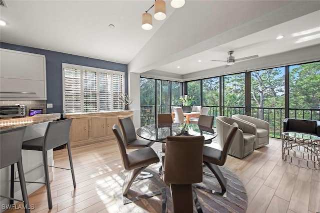 dining space with ceiling fan, lofted ceiling, and light wood-type flooring