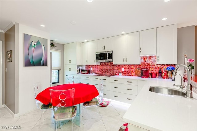 kitchen with sink, tasteful backsplash, white cabinets, stovetop, and light tile patterned flooring