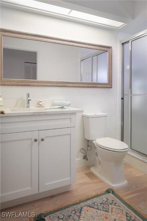 bathroom featuring hardwood / wood-style flooring, toilet, vanity, and walk in shower