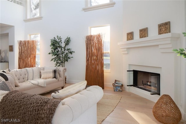 living room with a towering ceiling and light hardwood / wood-style flooring