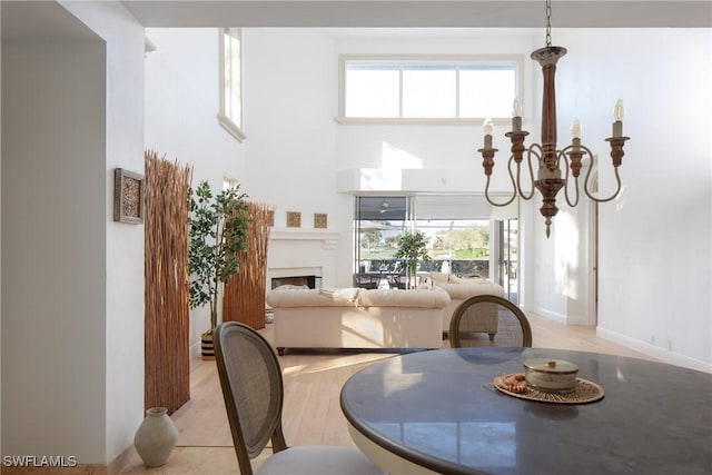 dining area featuring a towering ceiling, a notable chandelier, and light wood-type flooring