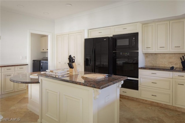 kitchen with cream cabinetry, black appliances, washer and dryer, and a kitchen island