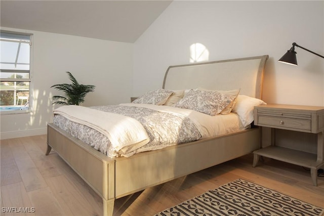 bedroom with lofted ceiling and light wood-type flooring