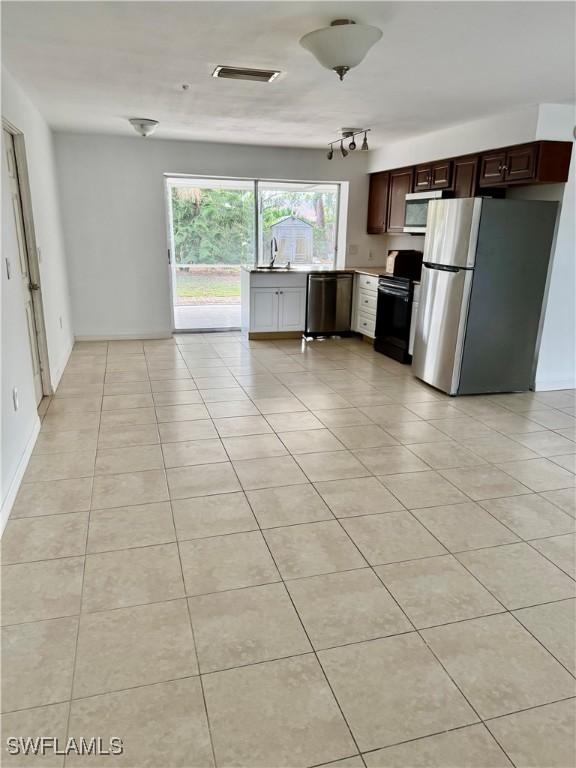 kitchen featuring appliances with stainless steel finishes, dark brown cabinets, light tile patterned flooring, and sink